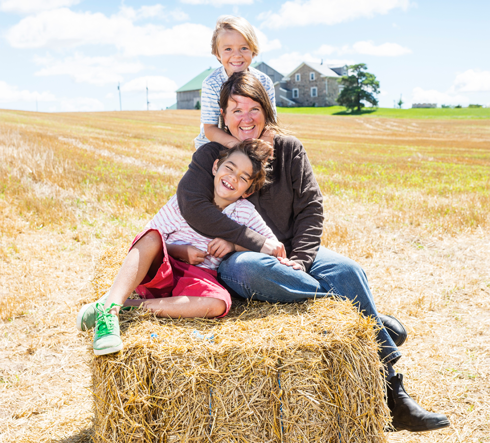 Woman farmer with children on hay bale