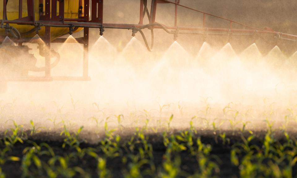 Tractor spraying pesticide onto field