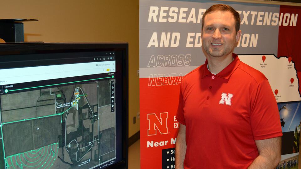 Nate Thorson stands beside screen displaying ag software