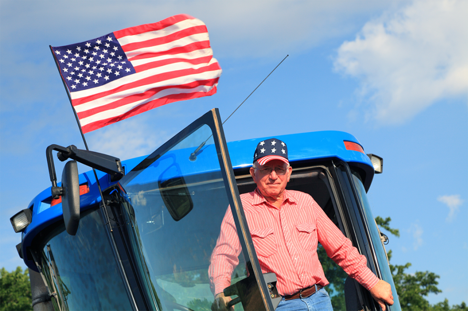 Farmer in tractor below flag