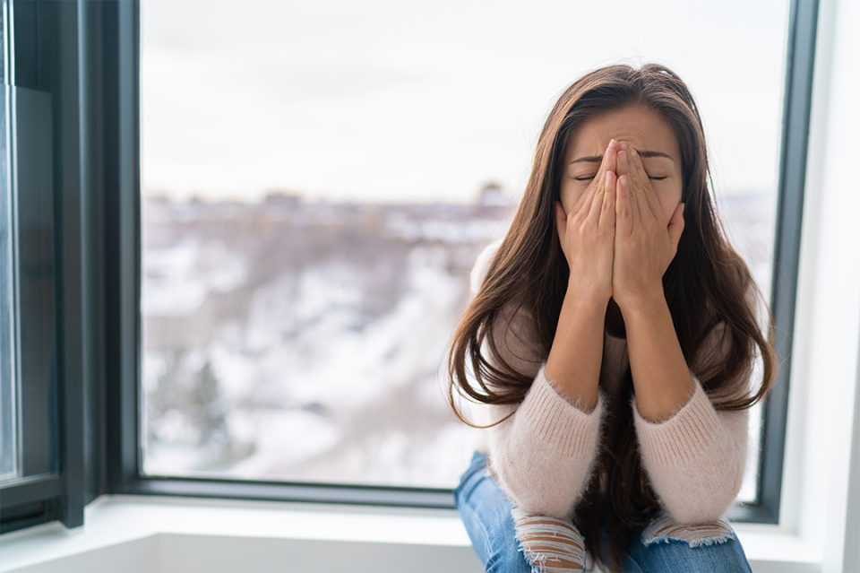 Woman with signs of stress in front of window during winter