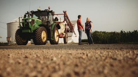 Man and woman speaking near tractor