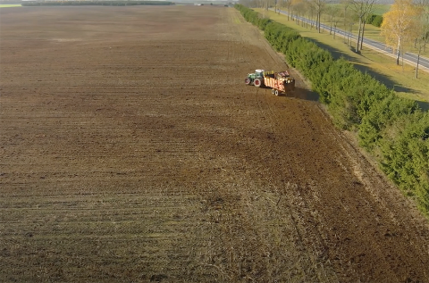 Aerial view of tractor applying fertilizer to planted field