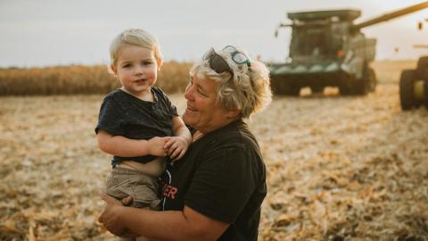 Woman holds young boy on farm