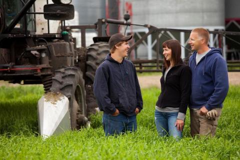 Couple and son laughing on farm beside tractor