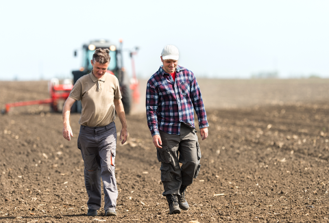Two men smiling and walking side-by-side in field